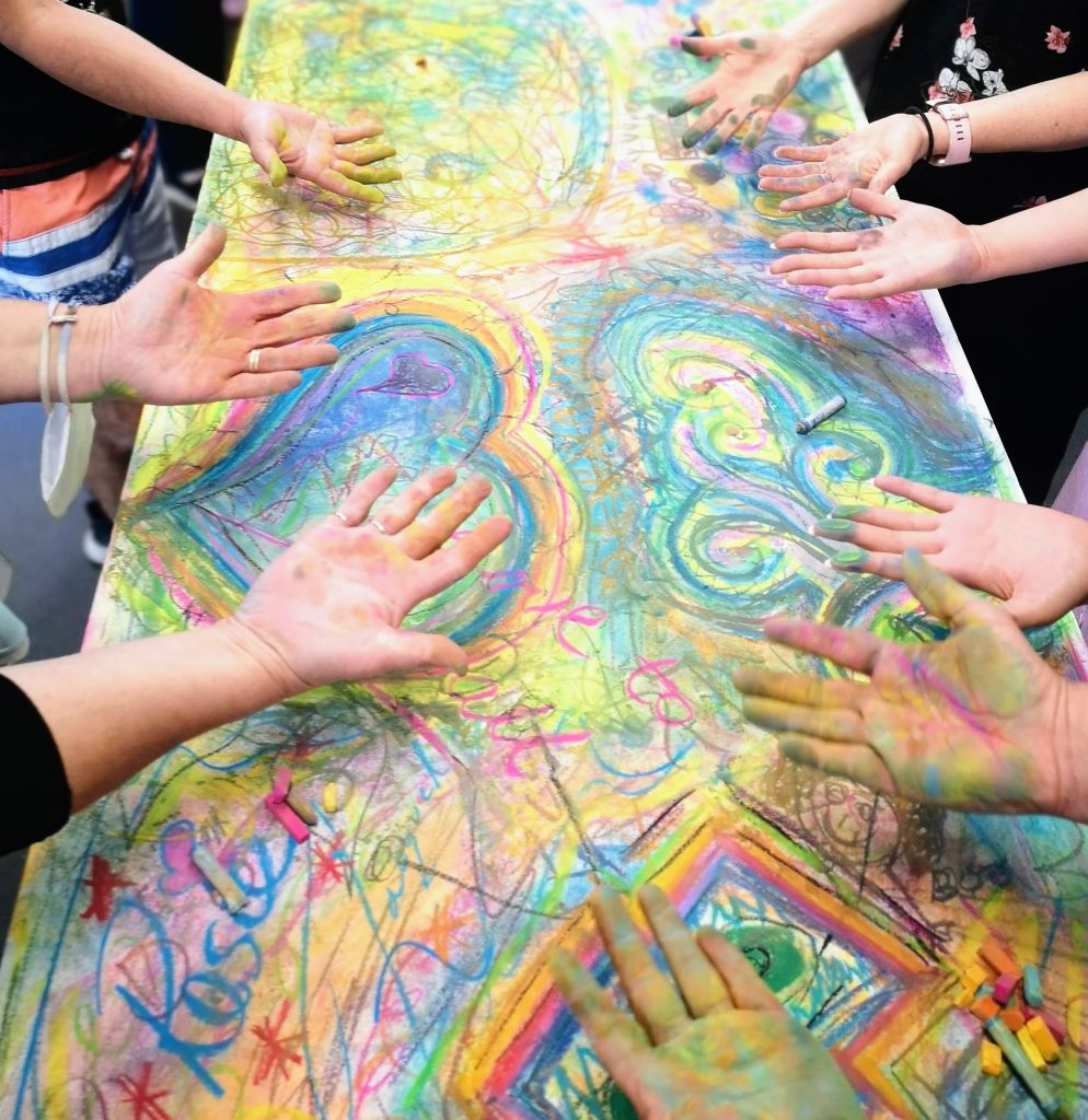 Group members painting together on a large shared artwork